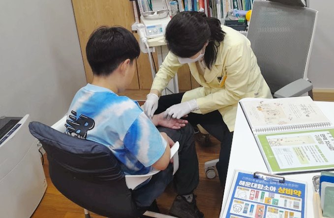 함소아한의원 해운대점 생활·환경 코칭: 진료실에서 아이와 자료를 함께 보며 설명하는 원장