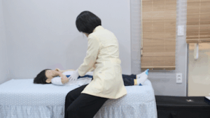 진료실 침대에 앉은 아이의 호흡 상태를 살펴보는 원장