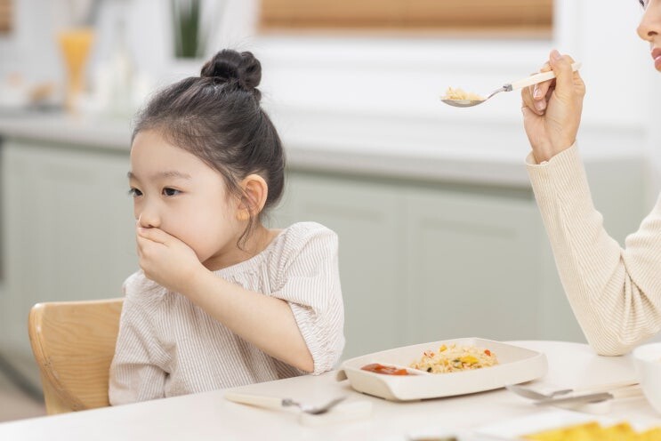 식탁에서 숟가락을 밀어내며 입을 가리고 식사를 거부하는 아이