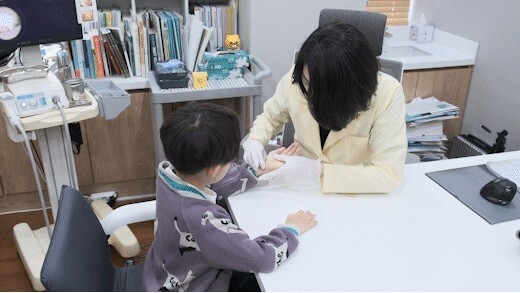 진료실 책상에서 아이와 마주 앉아 상담하는 안예지 원장