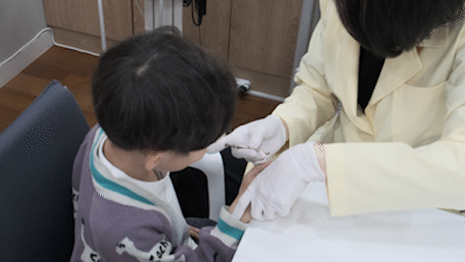 아이의 맥을 짚으며 상태를 확인하는 진료 장면