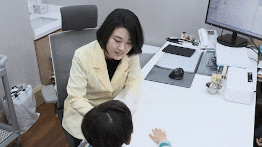 진료실 책상에서 아이를 맞이하며 상담하는 안예지 원장