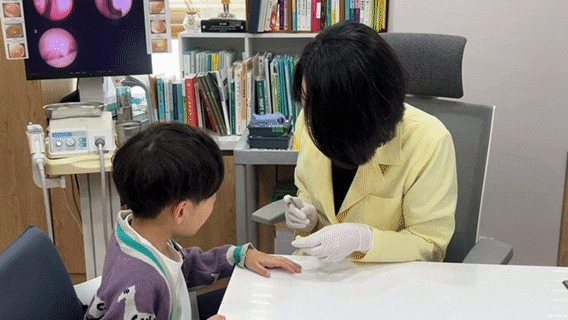 함소아한의원 부산 해운대점에서 아이의 팔에 치료 기기를 대는 원장