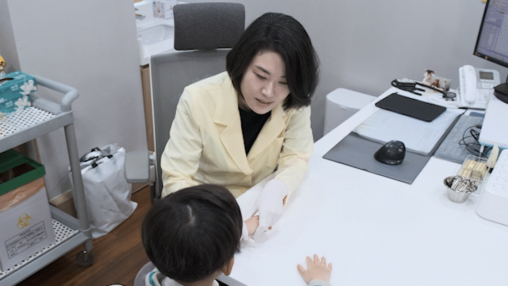 한의사가 보호자와 아이를 앞에 두고 상담하는 진료실 장면