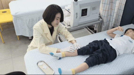 진료 침대에서 아이의 다리를 치료하는 한의사