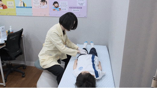 진료실 침대에서 아이를 살펴보는 한의사