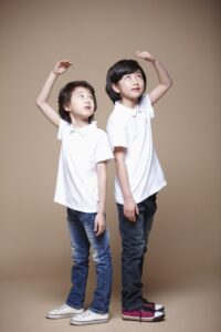 두 아이가 나란히 서서 키를 비교하는 모습